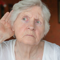 Bildet viser en eldre dame som har hånden bak øret for å lytte.