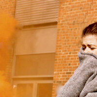 Bildet viser en skadet kvinne med et pledd rundt seg. Det er røykskyer rundt henne.