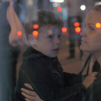 Bildet viser en kvinne som stirrer ut av et vindu med et barn på fanget