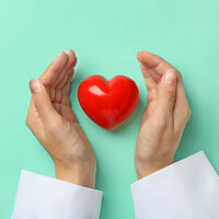 Bildet viser hendene til en sykepleier som holder rundt et hjerte