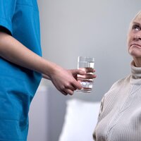 En sykepleier gir medisiner til en person med demens