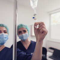 Bildet viser to sykepleiere som sjekker væske til en pasient.