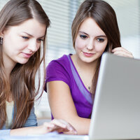 Bildet viser to kvinnelige studenter som ser inn i en pc-skjerm.