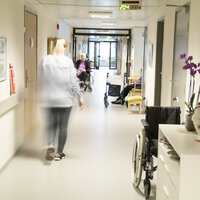 Sykepleier som går nedover en sykehjemskorridor.