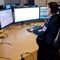 Bildet viser en AMK-sykepleier på AMK-sentralen. Hun sitter foran fire store skjermer og svarer på 113-samtaler