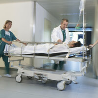Pasient blir flyttet i seng på et sykehus