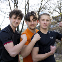 Bildet viser tre unge gutter i treningsklær som flekser muskler