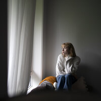 Bildet viser en kvinne som sitter ved et vindu.