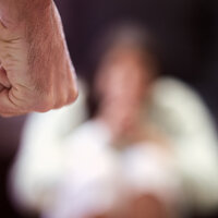 Bildet viser en knytteneve med en person i bakgrunnen som er redd