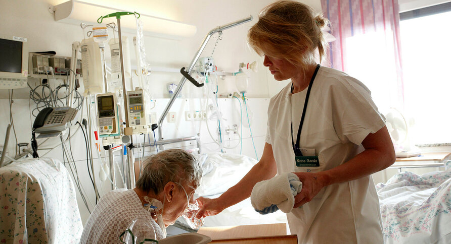 Sykepleier gir pasient noe å drikke